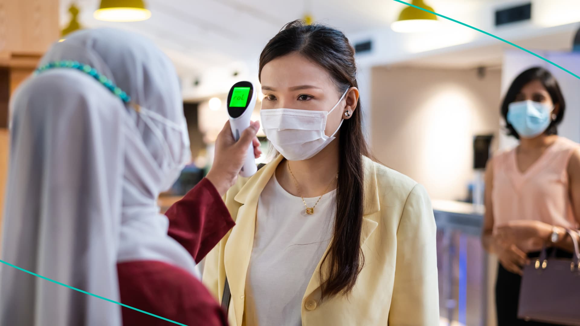 Team of business professionals wearing face mask sitting in office boardroom during a meeting.