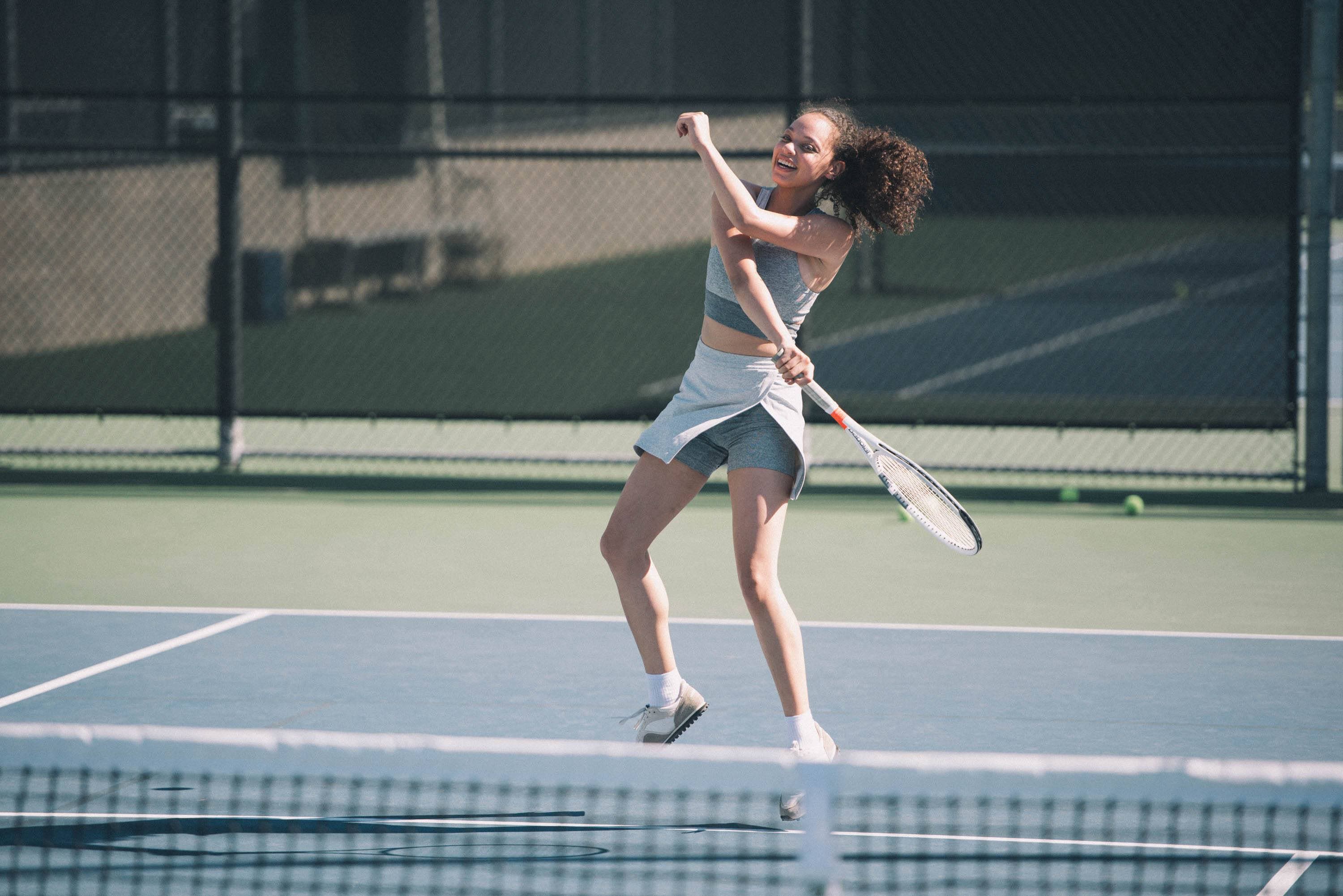 Woman playing tennis wearing workout Court Skort by Outdoor Voices