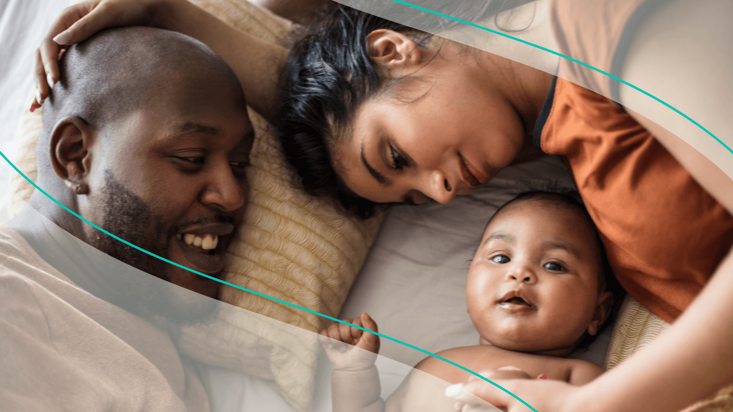 mother and father snuggle baby in bed
