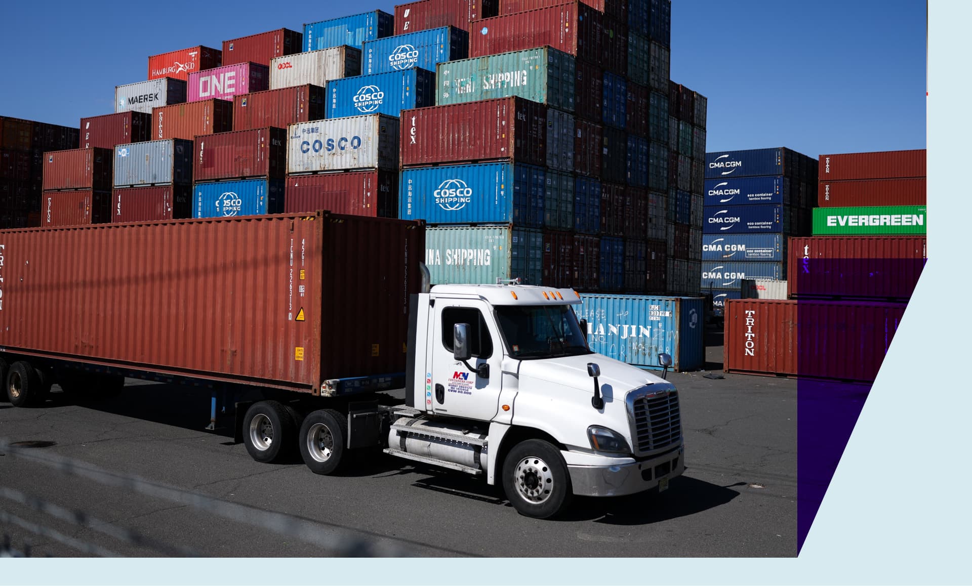 A truck carrying a shipping container drives past a stack of shipping containers at the Port Newark Container Terminal in Newark, New Jersey on April 8, 2025