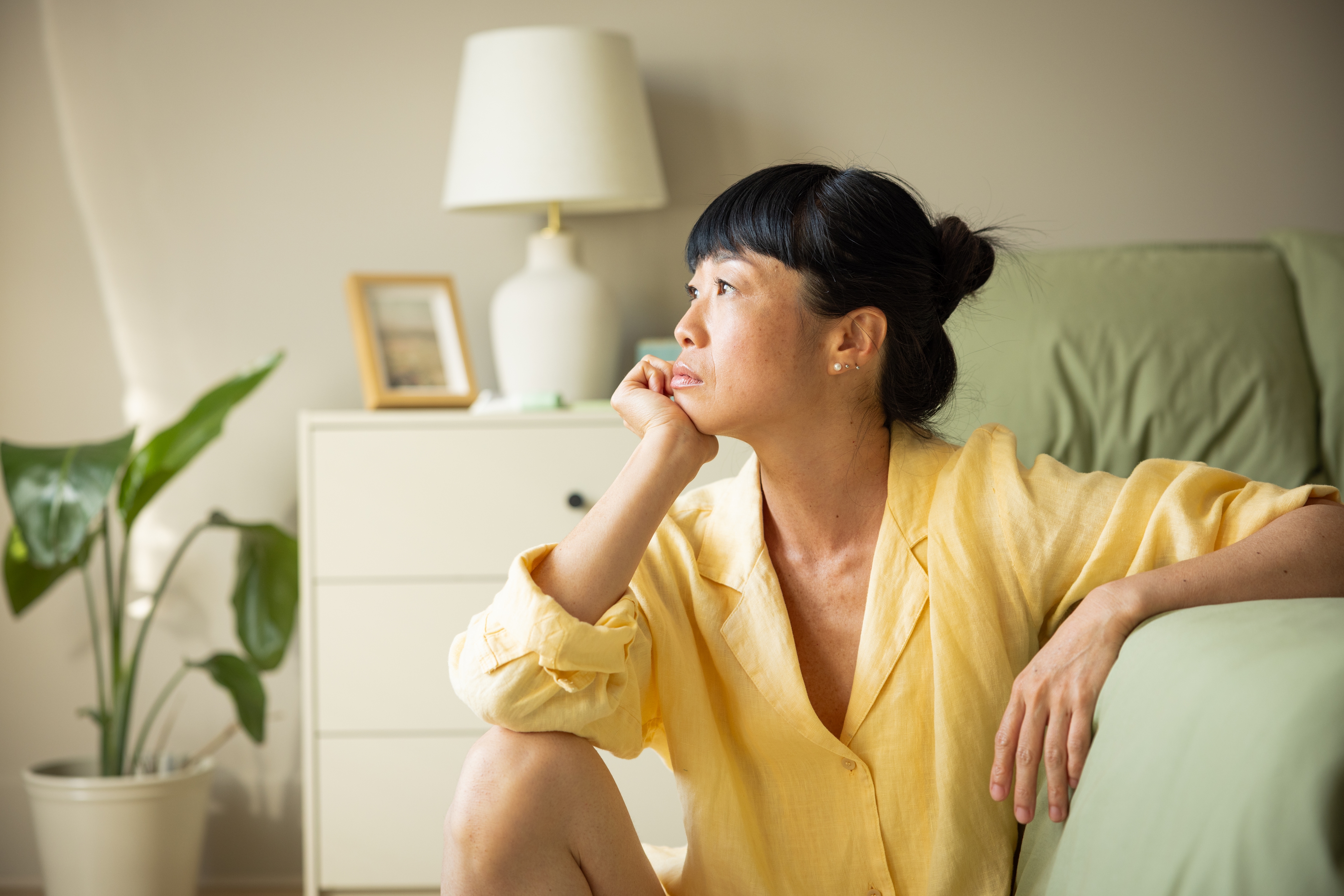 Woman with headache sitting on the floor at the side of her bed