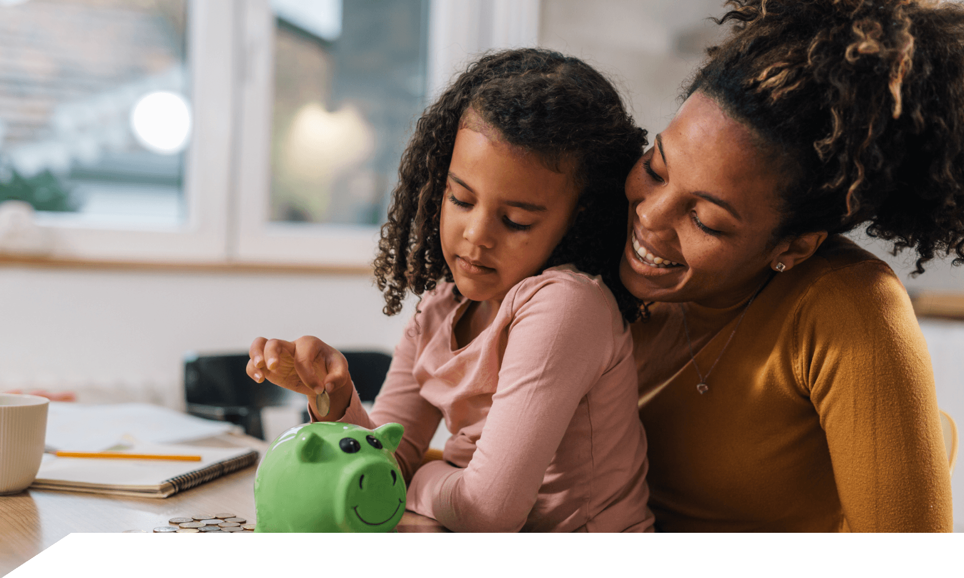 mom and daughter putting money in piggy bank