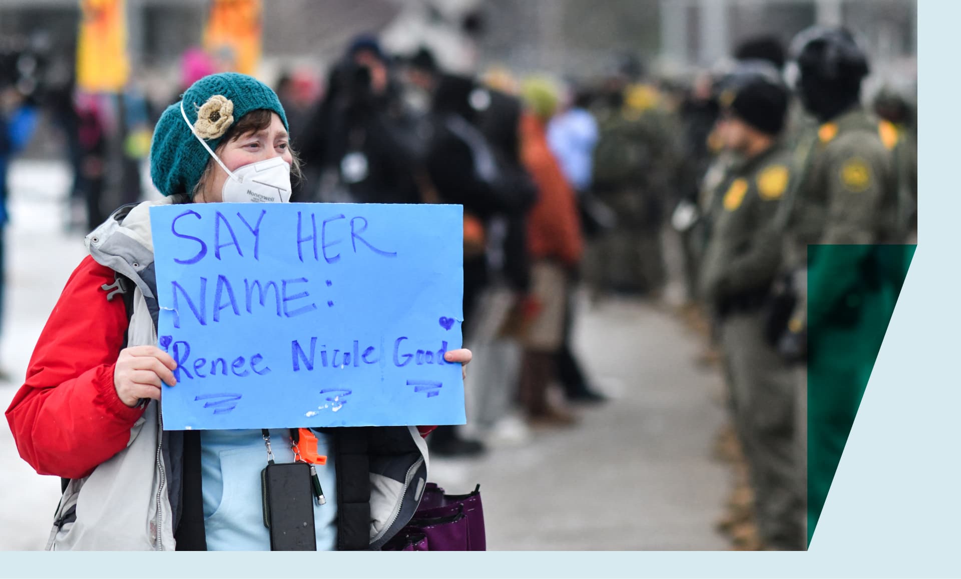 A protestor holds a sign as federal agents stand guard as protestors gather outside the Bishop Henry Whipple Federal Building in Saint Paul, Minnesota, on January 8,