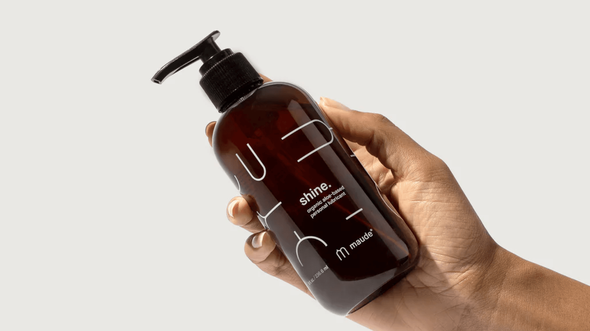 Hand holding translucent brown bottle of lube