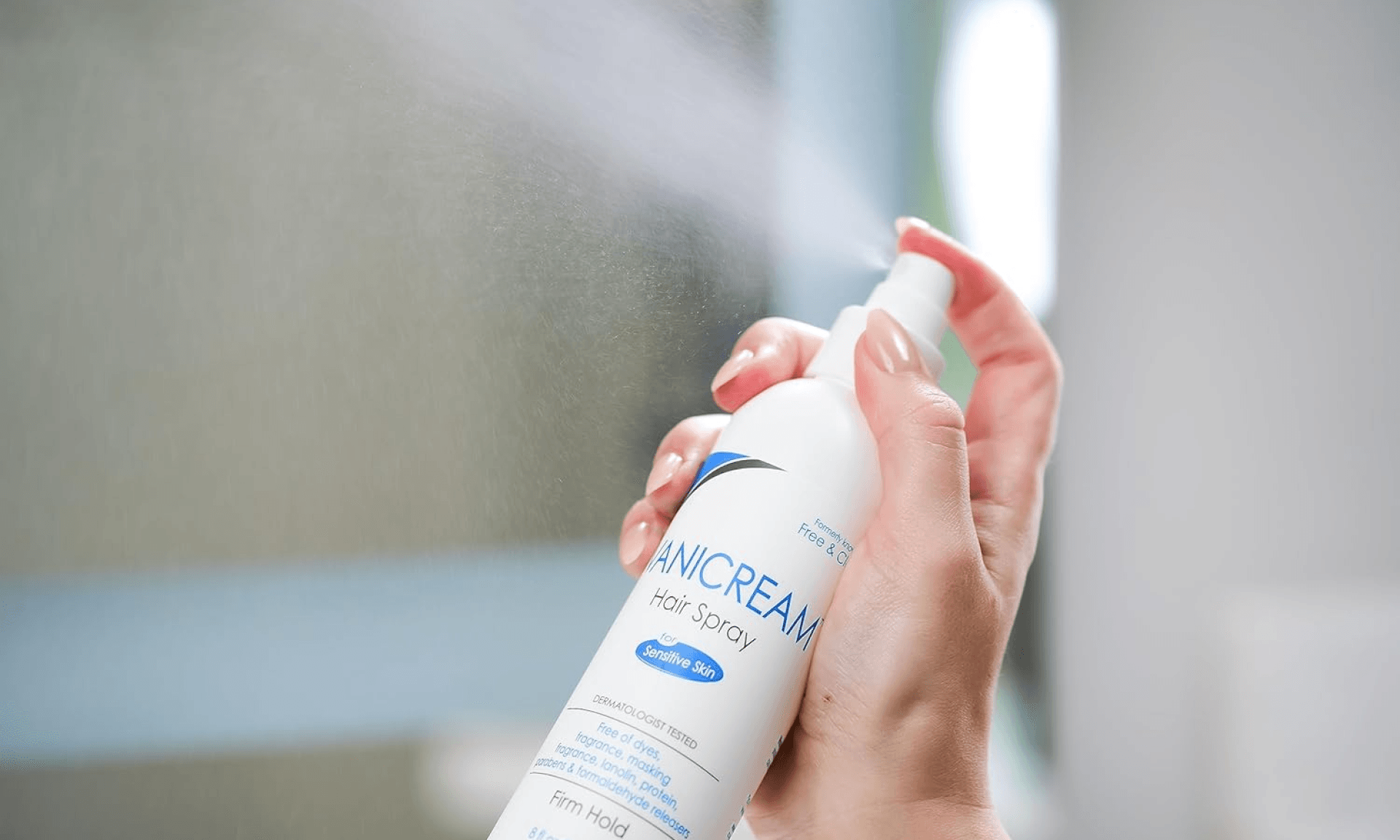 Hand spraying Vanicream hair spray into air