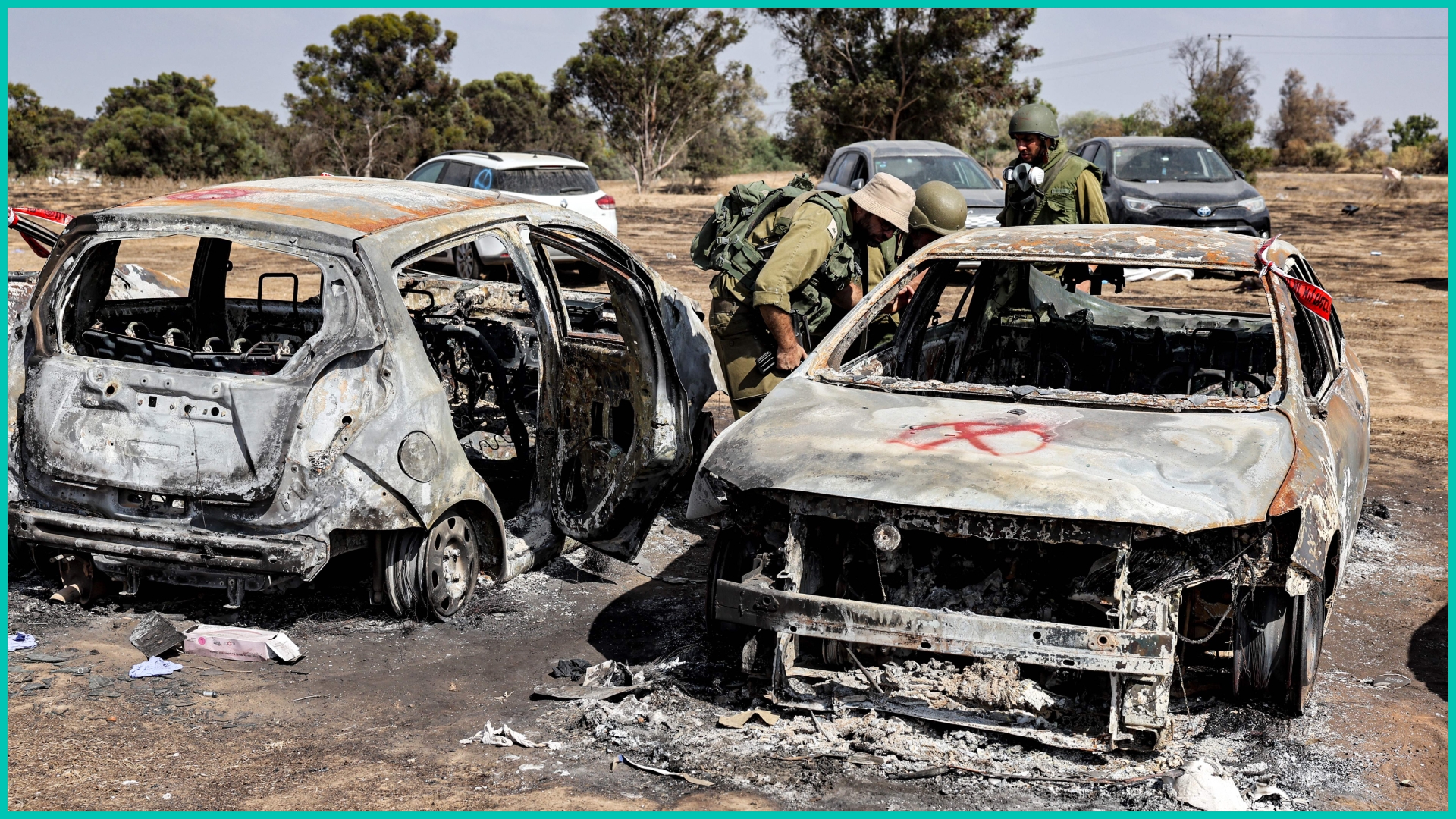 Israeli soldiers near a kibbutz in southern Israel search vehicles torched by Hamas during its Oct. 7, 2023 attack on Israel.